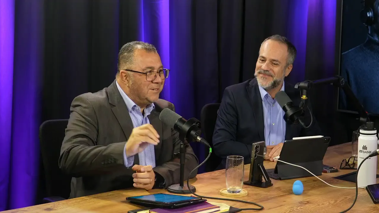 Dois executivos em estúdio conversando de forma engajada, com microfones e mesa