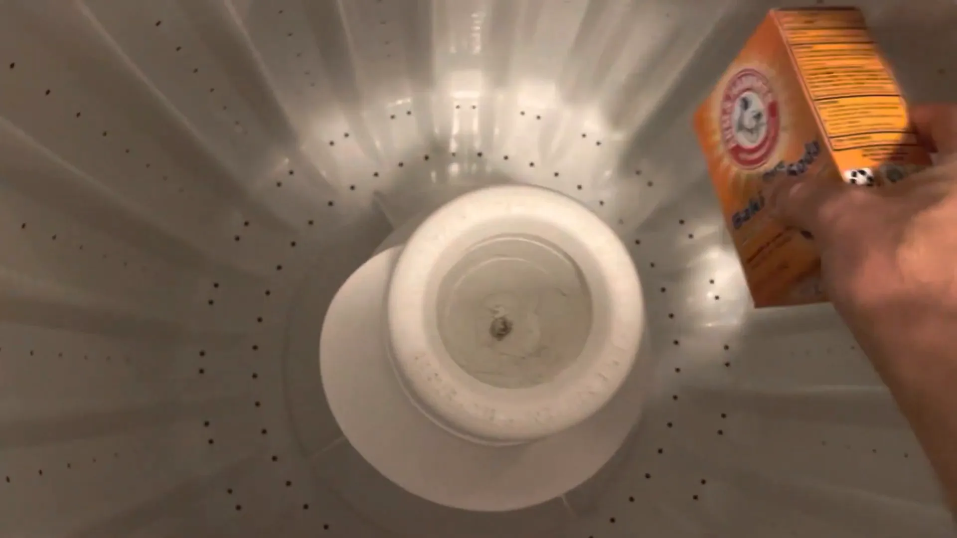 Emptying a box of baking soda into the washing machine