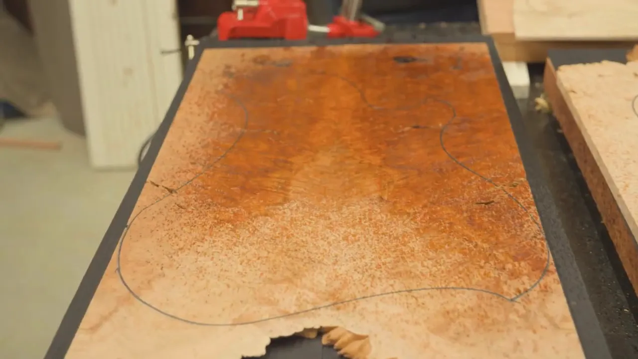 Figured amber-toned guitar top blank with outline on a workbench