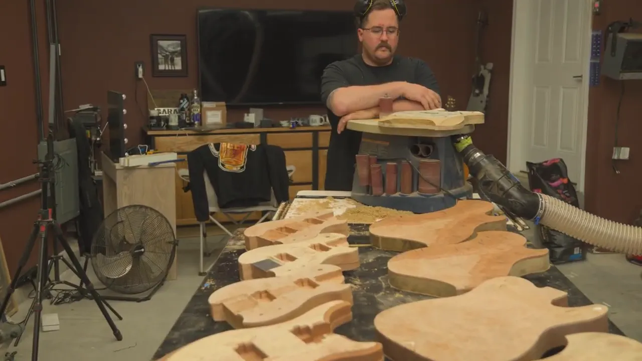 Woodworker at a CNC/bench with multiple guitar body blanks ready for edge profiling