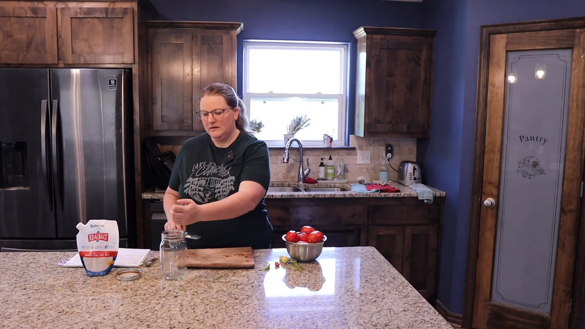 Woman adding crushed garlic to a jar in order to make fermented tomato sauce