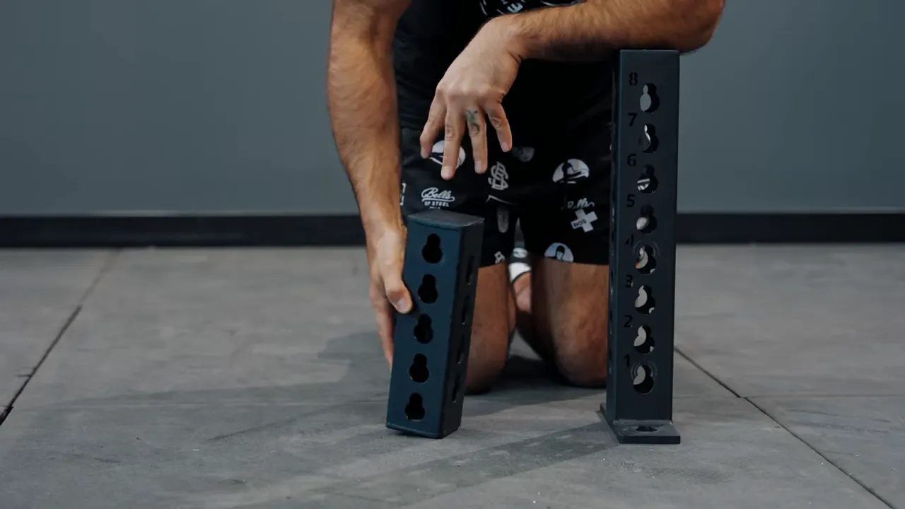 Box and stand rack junctions side-by-side on the floor showing keyhole patterns and numbered holes on the taller piece.