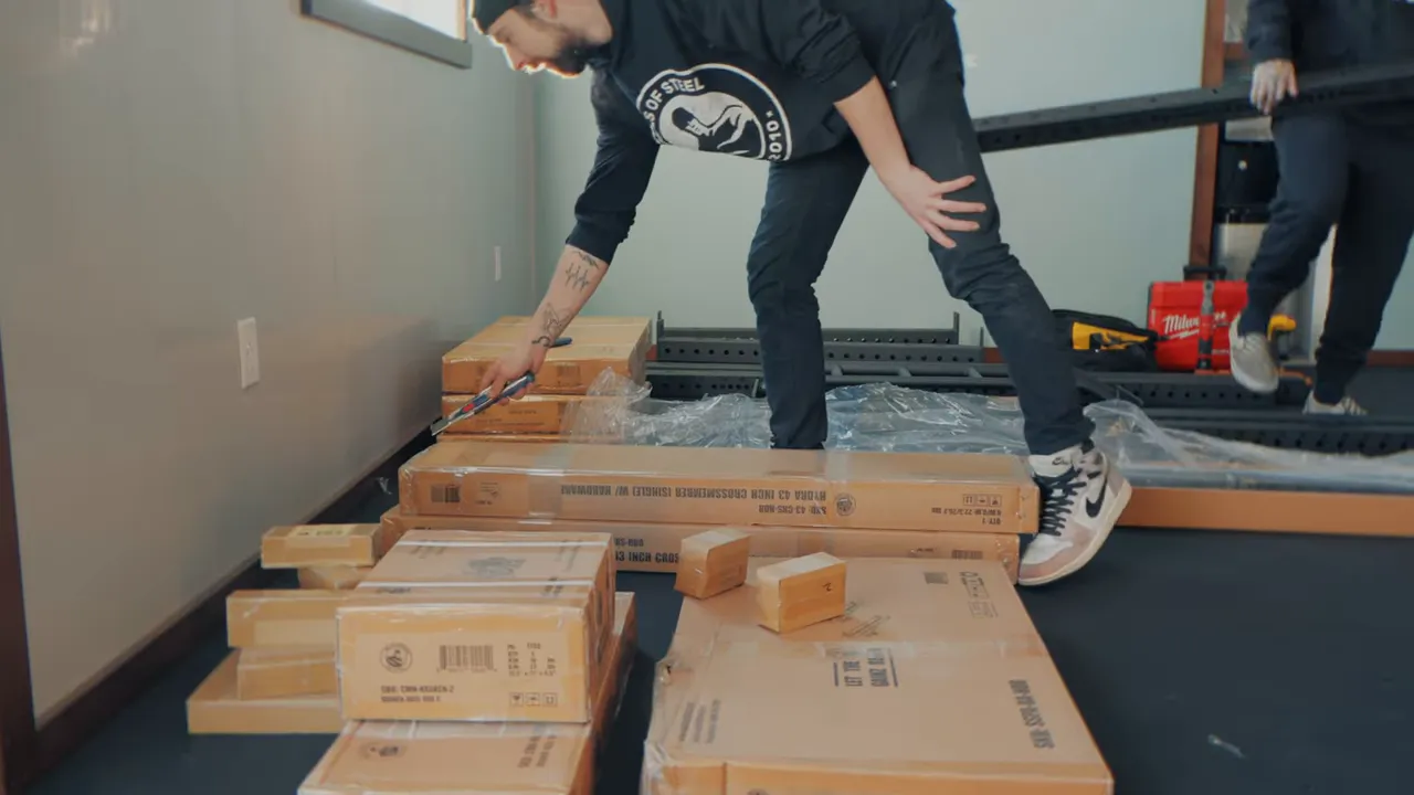Installers unboxing and arranging power rack parts and hardware on the gym floor