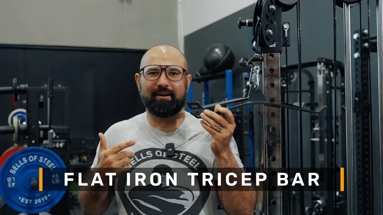 close-up of a presenter holding the flat iron tricep bar with on-screen title text
