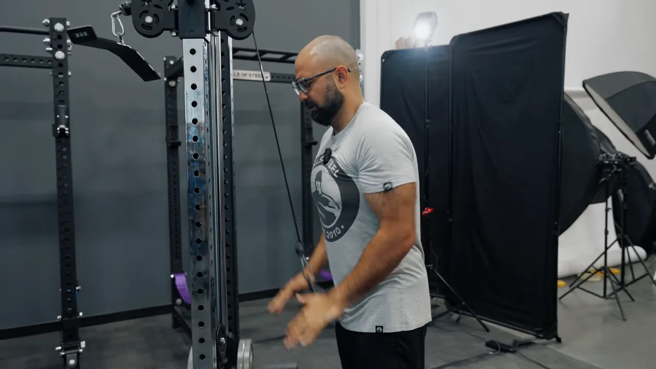 trainer performing a palm-press tricep pressdown on the Flat Iron attachment at a cable machine