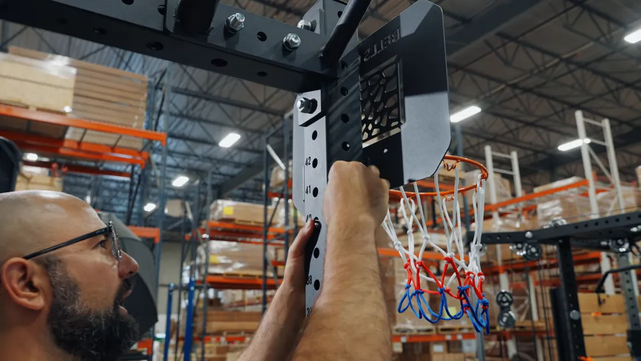 Close-up of the Bells of Steel Hoop 2.0 L-bracket with the mounting bolt aligned into the rack upright, showing the hoop and net.