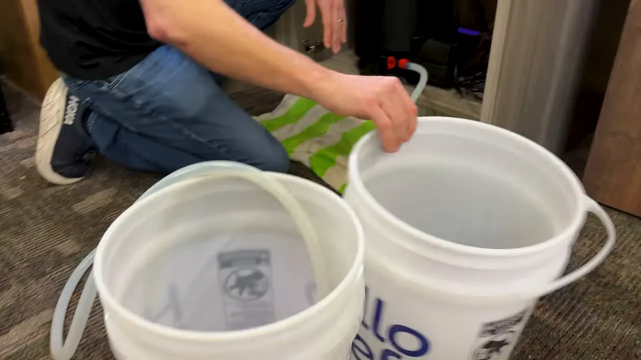 Flexible drain hose positioned inside a white bucket beside the Fluval FX6