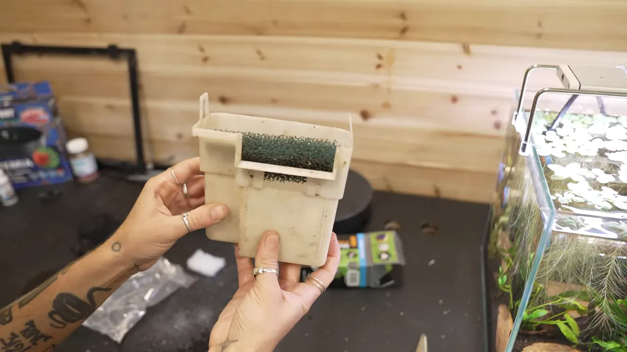 Hands holding a completed filter media basket with white floss and green sponge