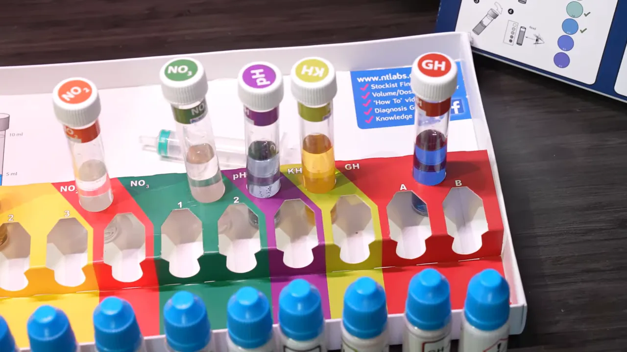 Six labelled aquarium water test tubes arranged above rows of reagent bottles