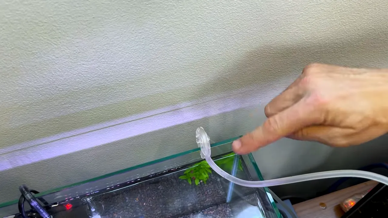 Clear CO2 tubing secured in a clip over the aquarium rim