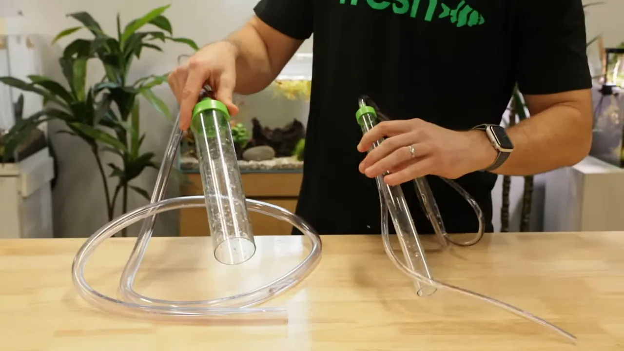 Two aquarium gravel vacuums with different tube widths on a wooden table
