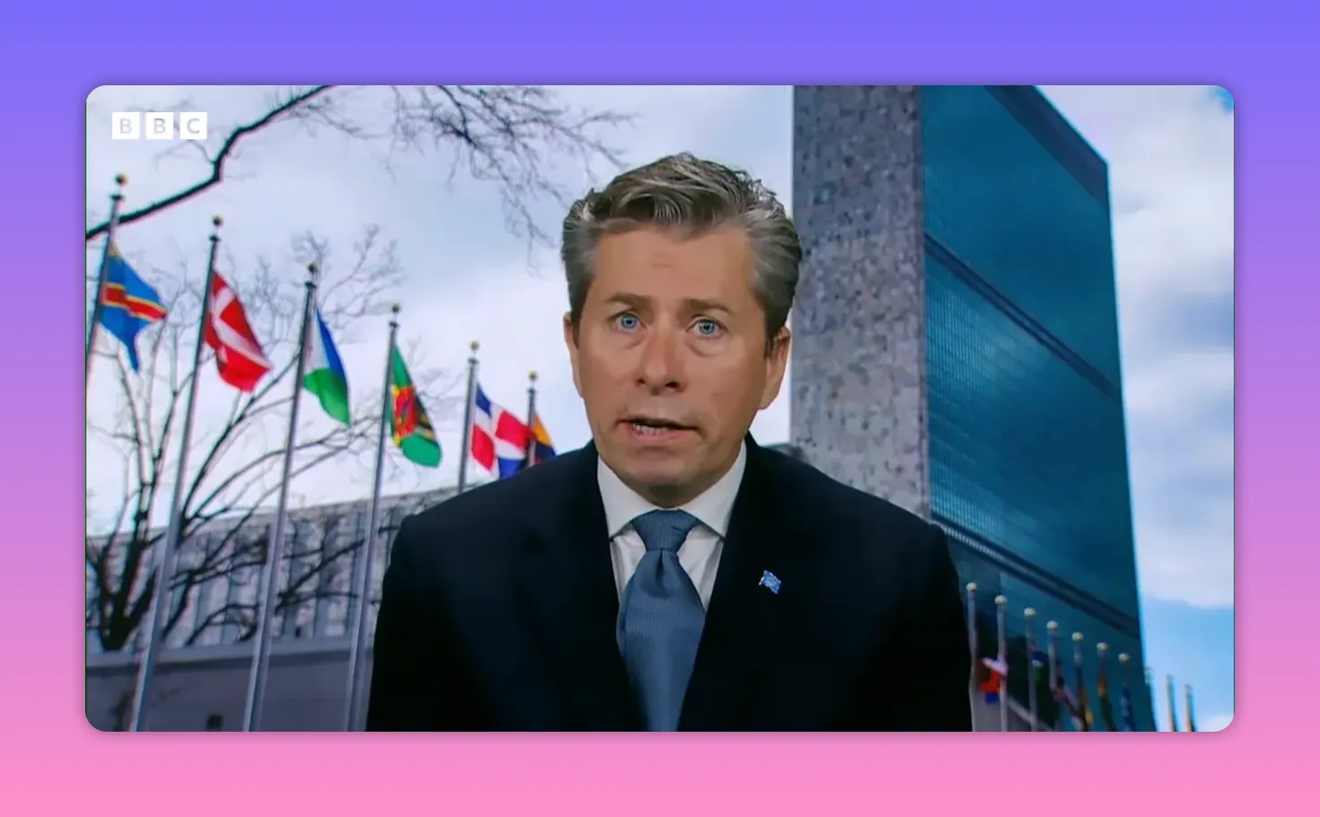Intervenant en entretien devant le siège de l'ONU avec une rangée de drapeaux visibles