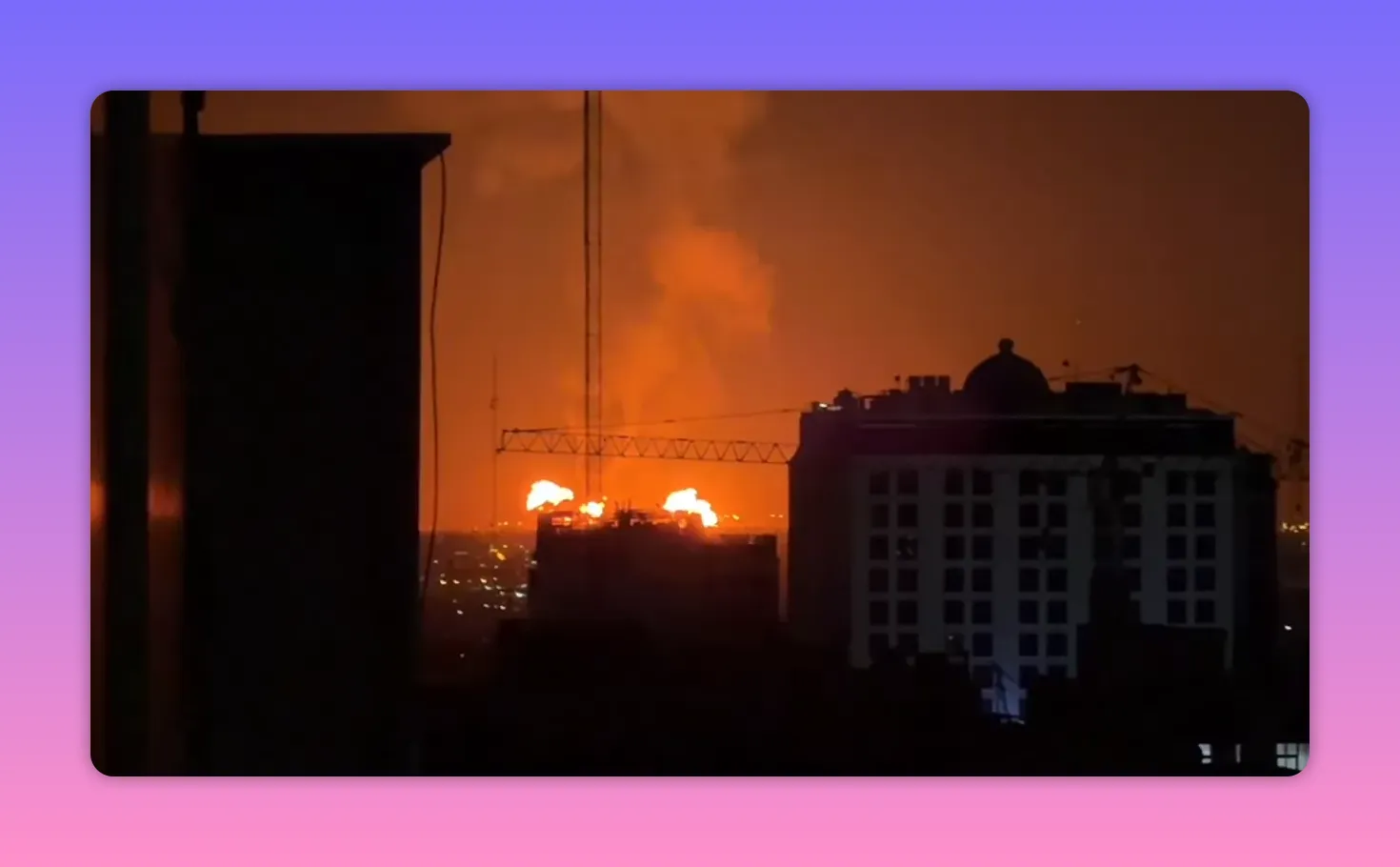 Flammes et fumée au-dessus d'un bâtiment la nuit avec une grue en silhouette