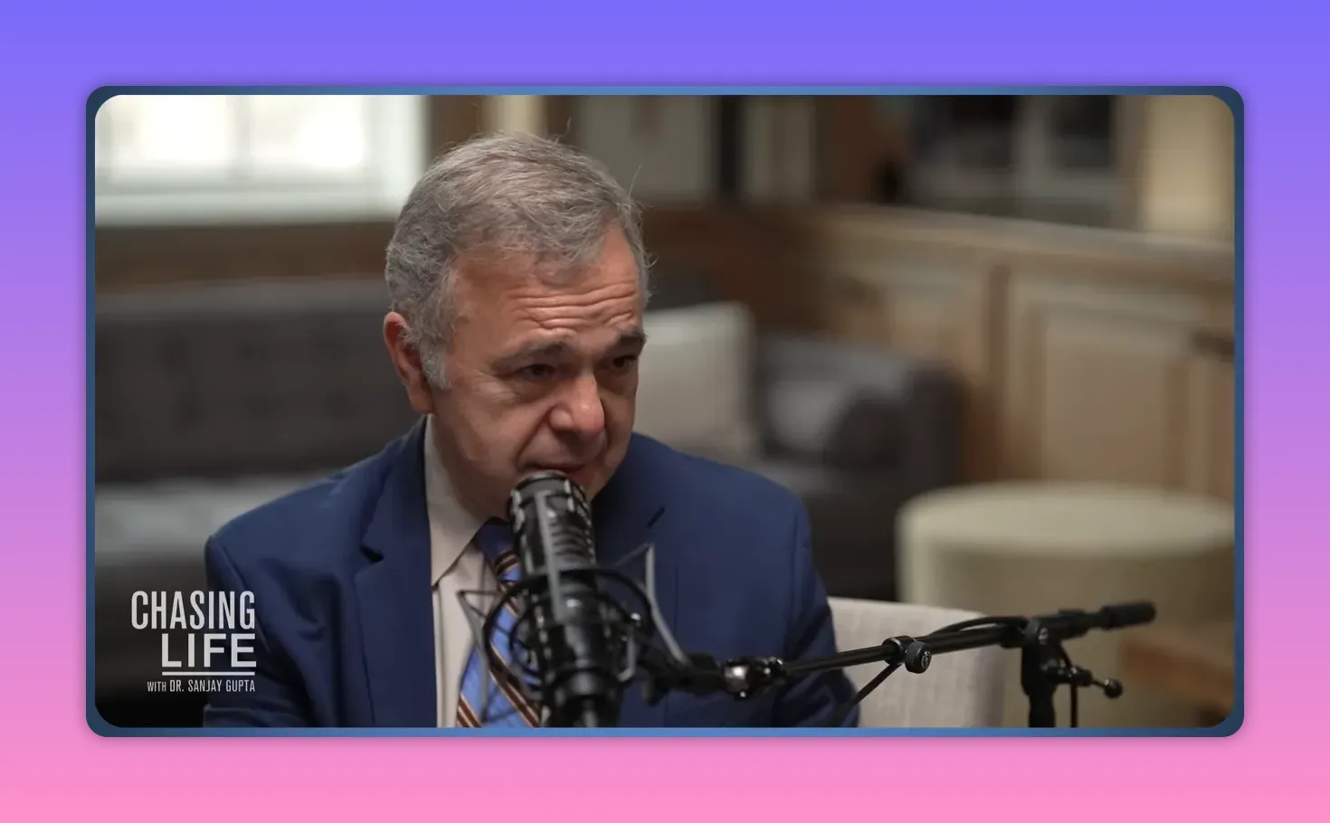 Nahaufnahme eines Podcast‑Gasts, der ins Mikrofon spricht; Studiohintergrund unscharf.