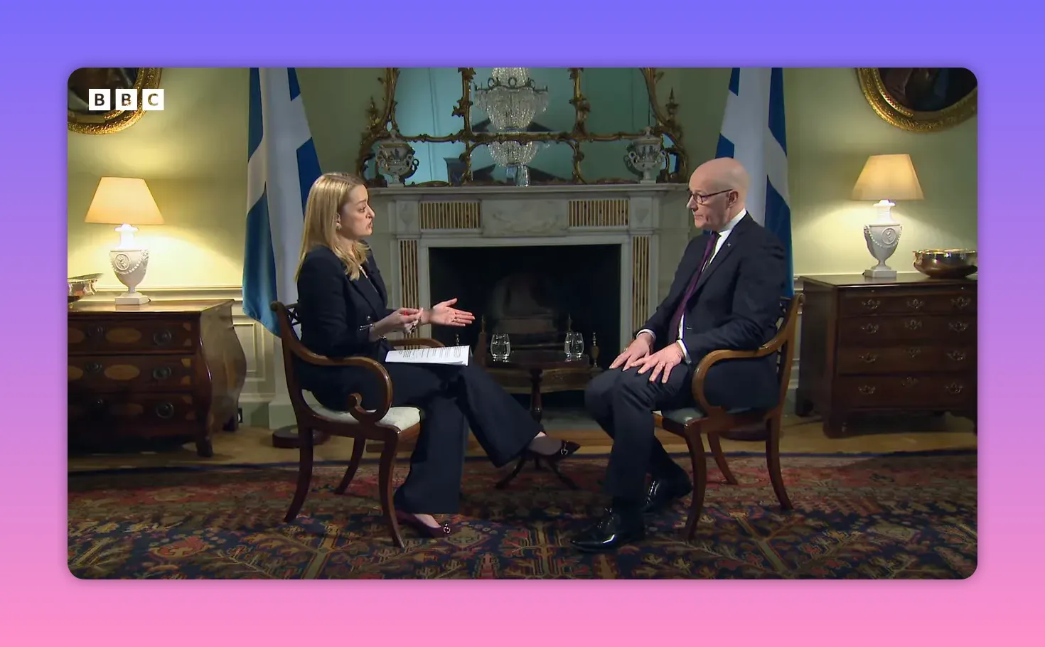 Plan large d'une interview en intérieur montrant deux personnes assises face à face dans un cadre officiel.