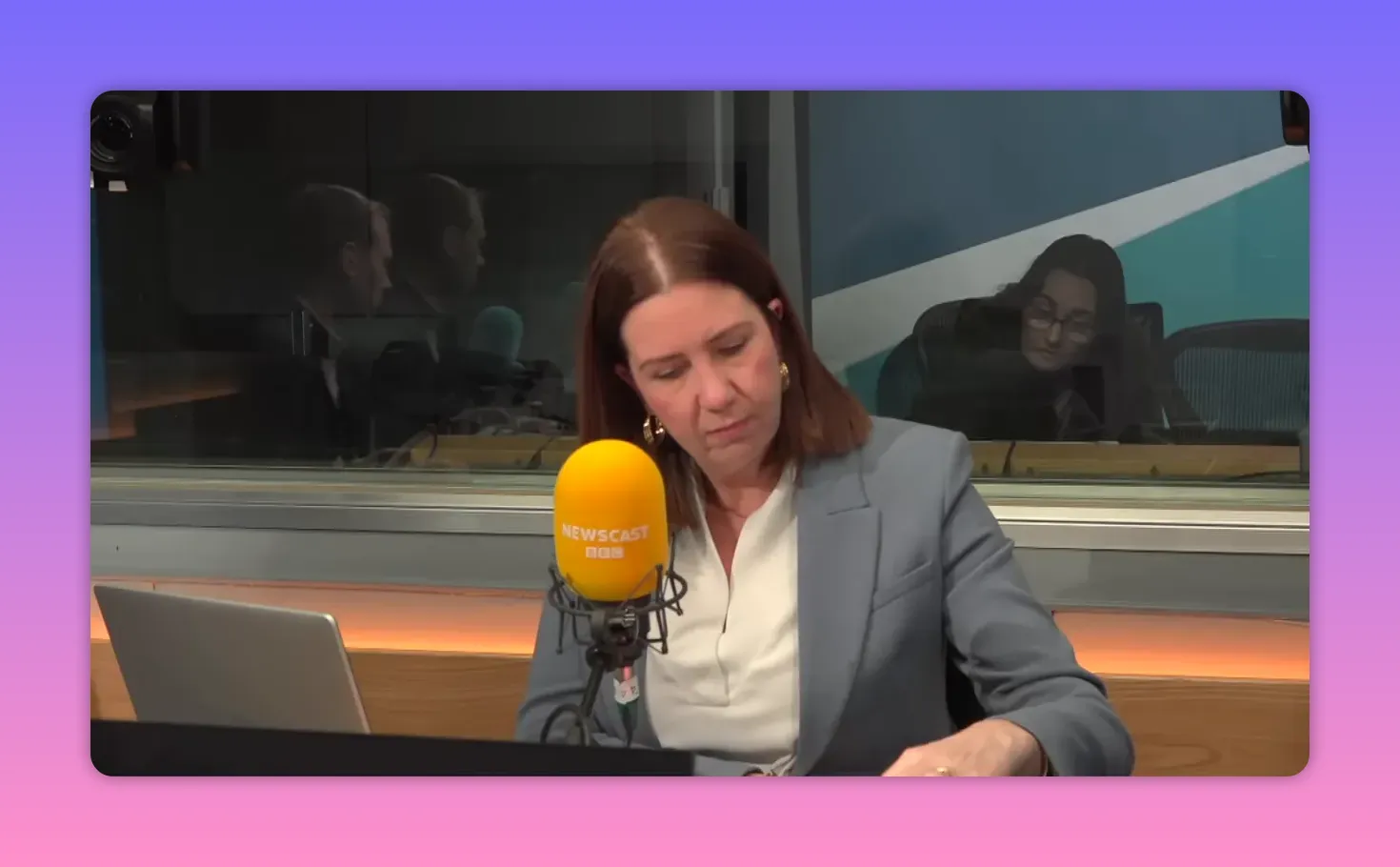 Journaliste consultant des documents et prenant des notes en studio, micro jaune Newscast visible