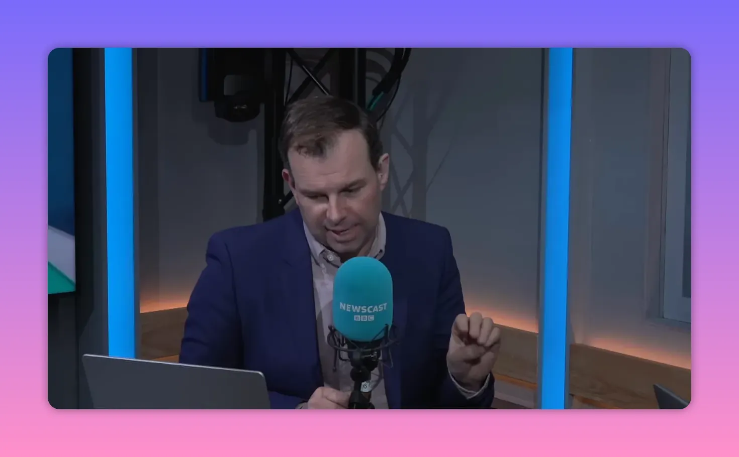 présentateur de radio faisant un geste explicatif devant un micro bleu Newscast