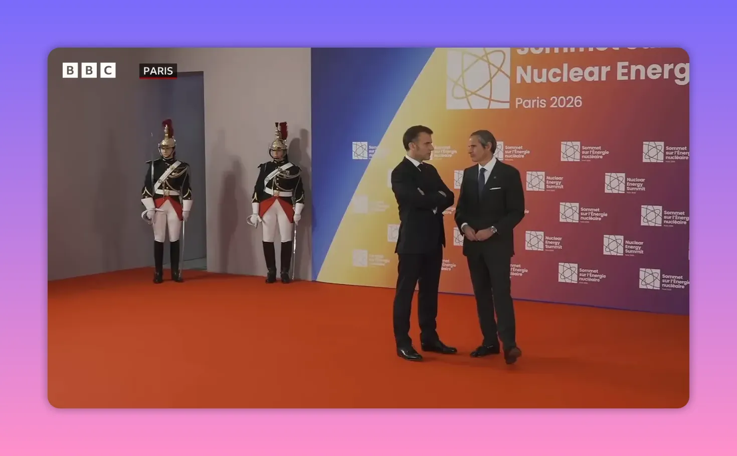 Participants en discussion devant le panneau 'Nuclear Energy Summit Paris 2026' avec deux gardes en tenue cérémonielle