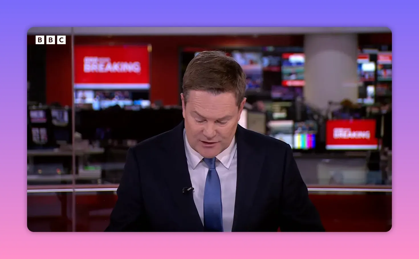 Présentateur BBC en gros plan sur le plateau, écran 'Breaking' visible dans la newsroom en arrière-plan