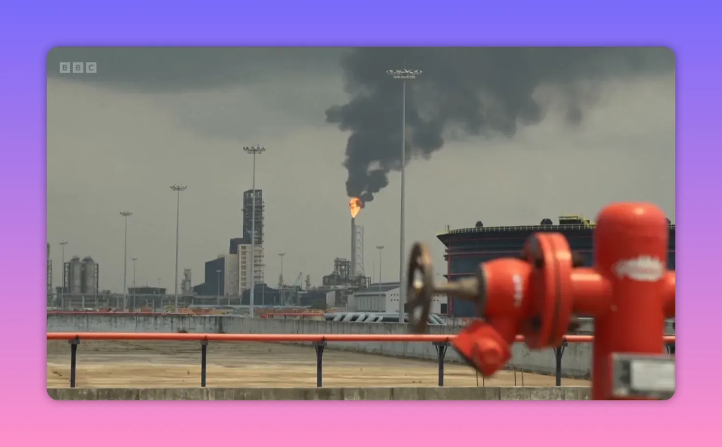 Raffinerie avec torchère en feu et panache de fumée noire, installation industrielle au premier plan