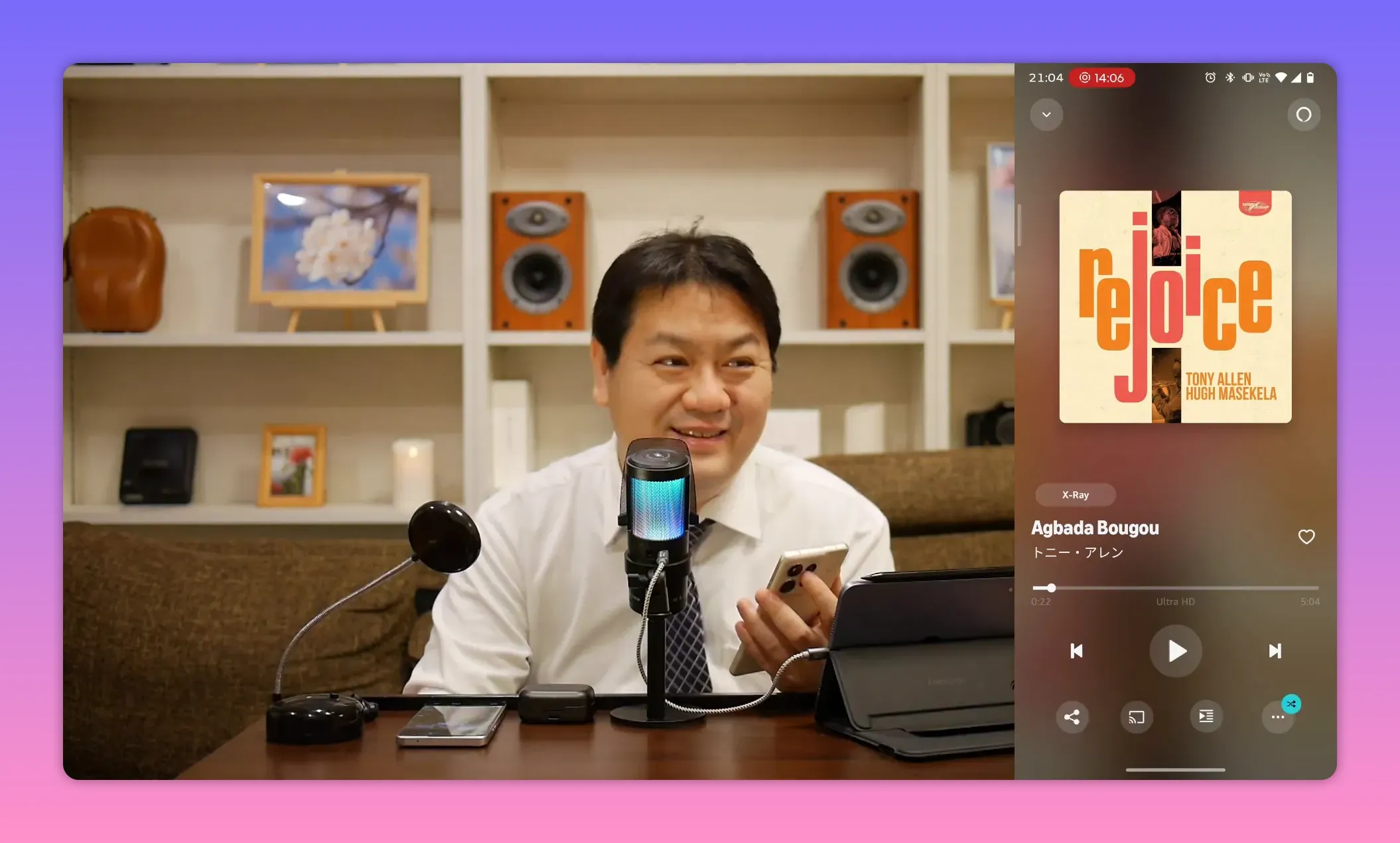 微笑むレビュワーがマイク越しに話す様子、右側に再生中の音楽画面とアルバムアートが見える