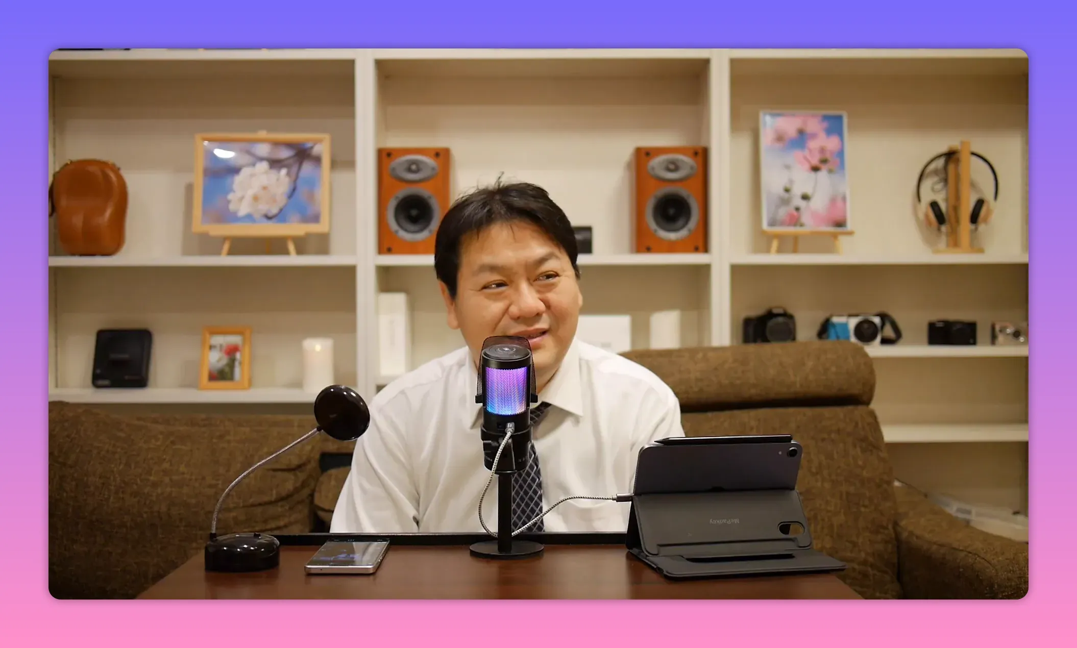 収録スタジオでマイクを中心に座る人物の定点ショット、字幕や画面テキストがないクリーンな構図