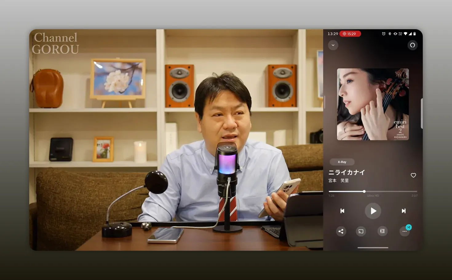 マイク前で説明する男性と右側に表示されたバイオリンのアルバムアートが見えるスマホの再生画面(字幕なしで画面が見やすい)