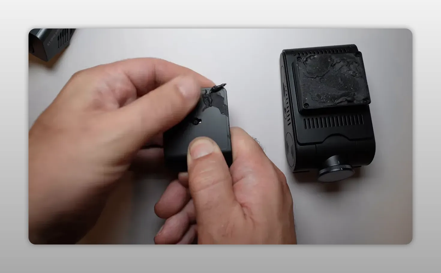 Hands peeling old adhesive from a square dash cam mount