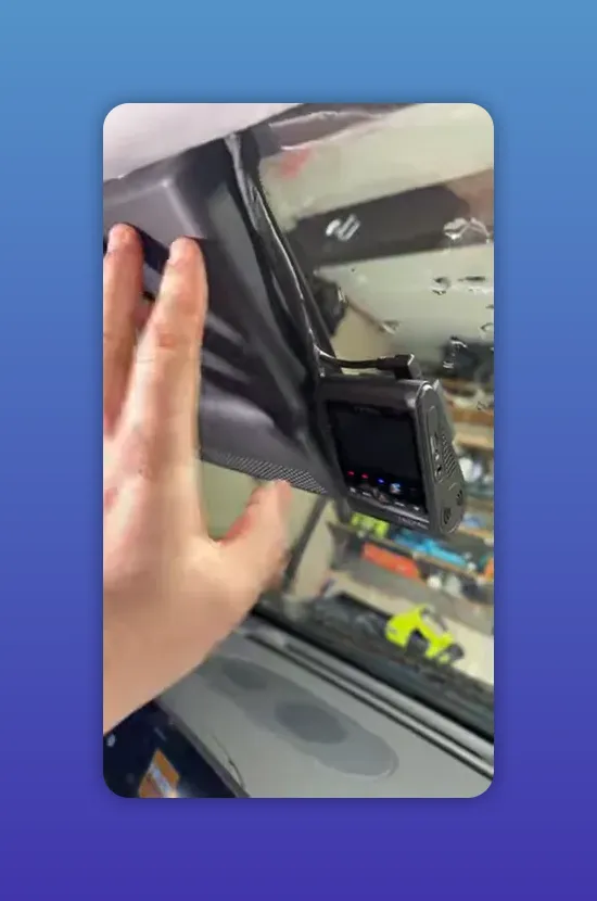 Hand pressing headliner trim back over dash cam to hide wiring