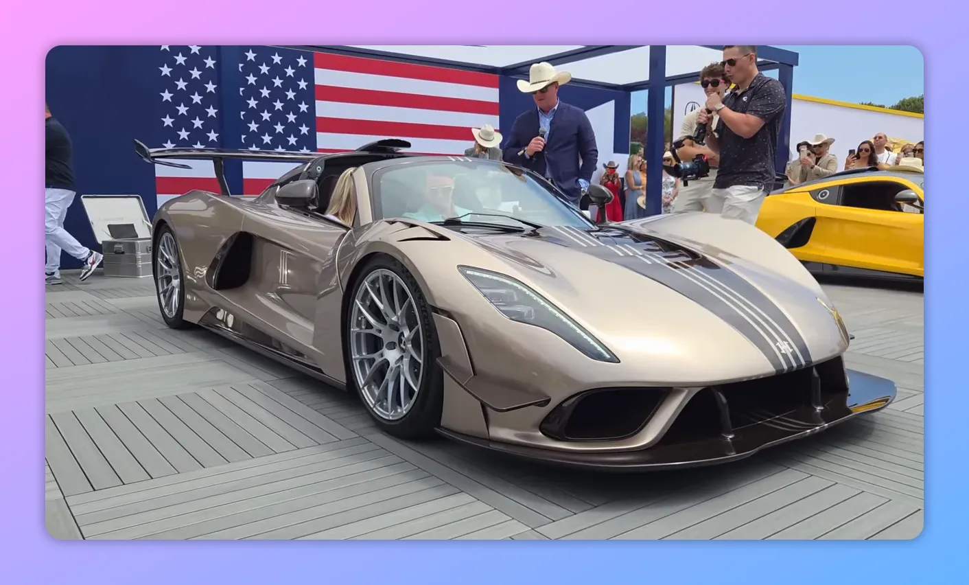 Cerimonia di consegna di una Hennessey Maverick su una pedana con presentatore al microfono, guidatore nella vettura e pubblico che osserva