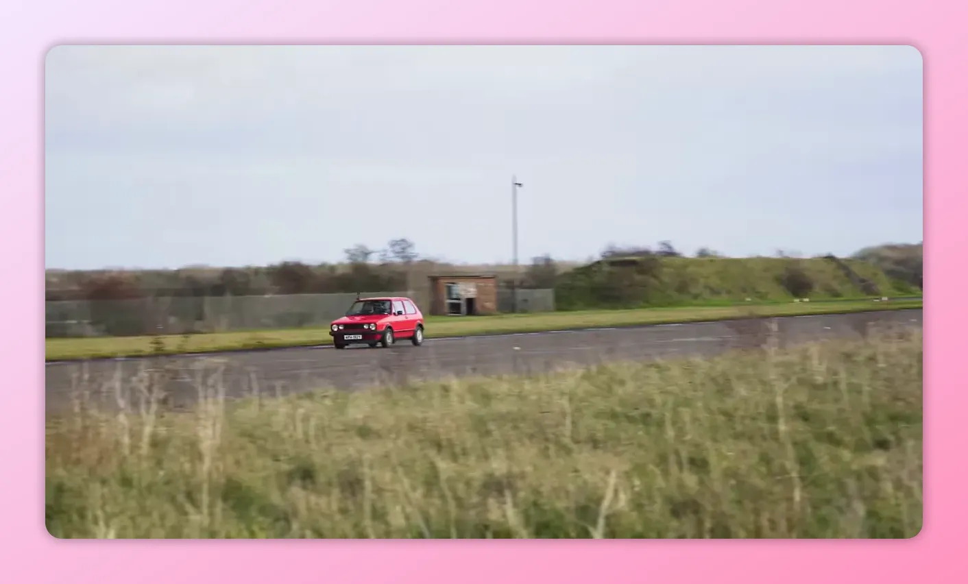 Hot-hatch rossa che accelera sul piazzale con lo sfondo degli hangar