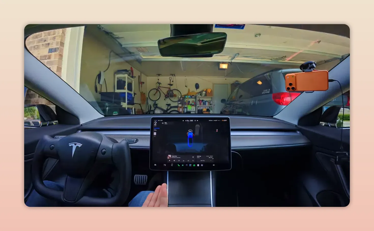車內視角顯示 Tesla 正緩慢駛入車庫，中控螢幕為停車與攝影畫面，車庫內可見腳踏車與收納架