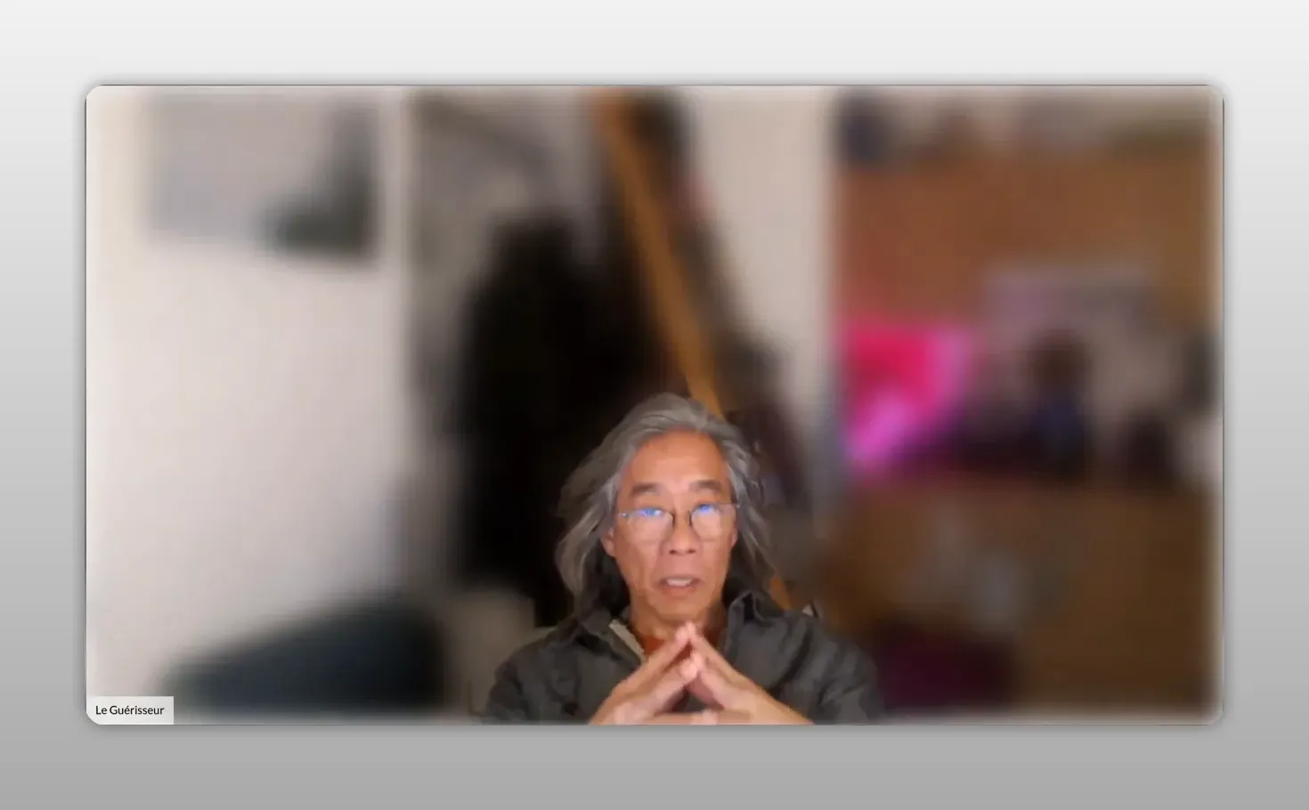 Orateur en webcam, mains jointes en triangle, fond flou