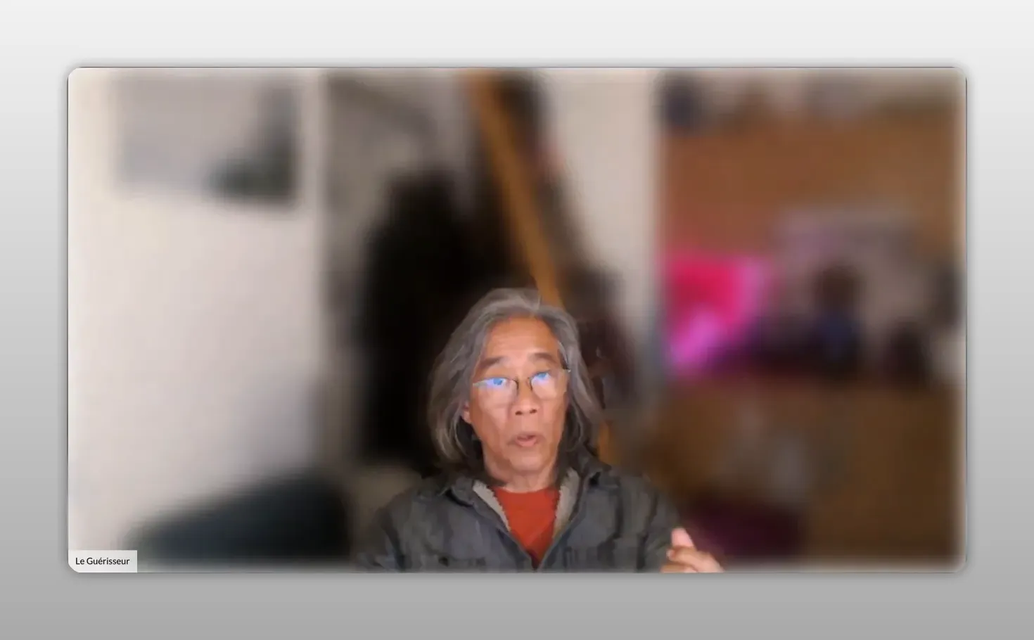 Intervenant en webcam, visage centré et net, léger geste de la main, arrière‑plan flou