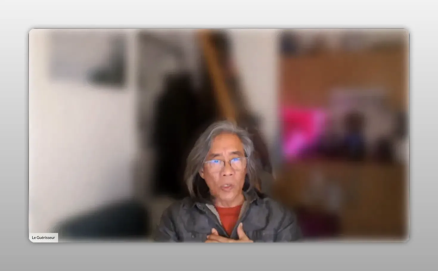 Intervenant à mi‑buste, mains proches de la poitrine, fond flou — posture d’ancrage respiratoire.