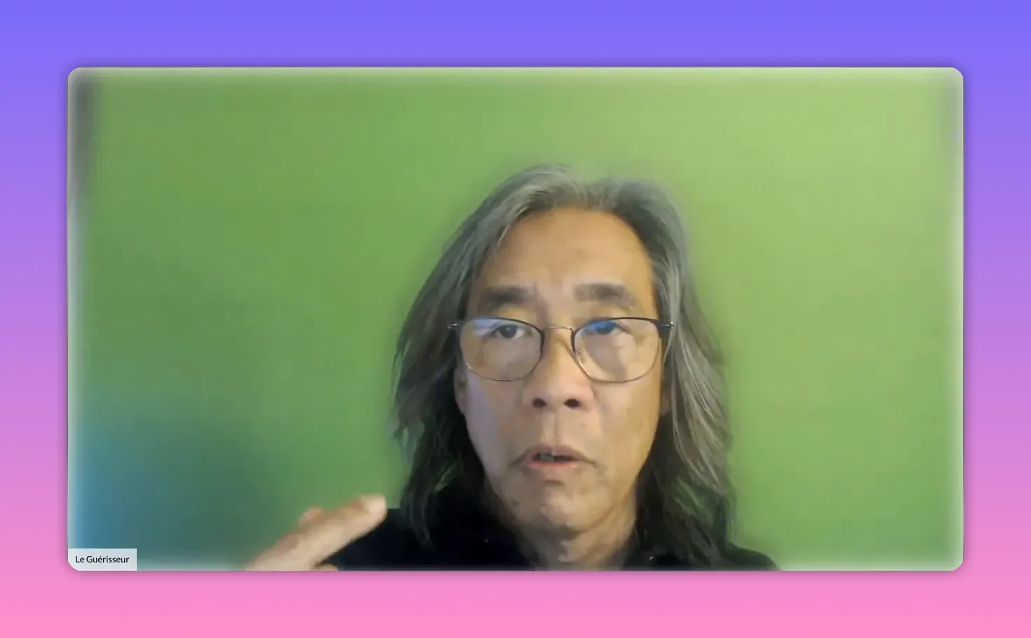 Intervenant regardant la caméra, main levée en geste explicatif devant un fond vert.