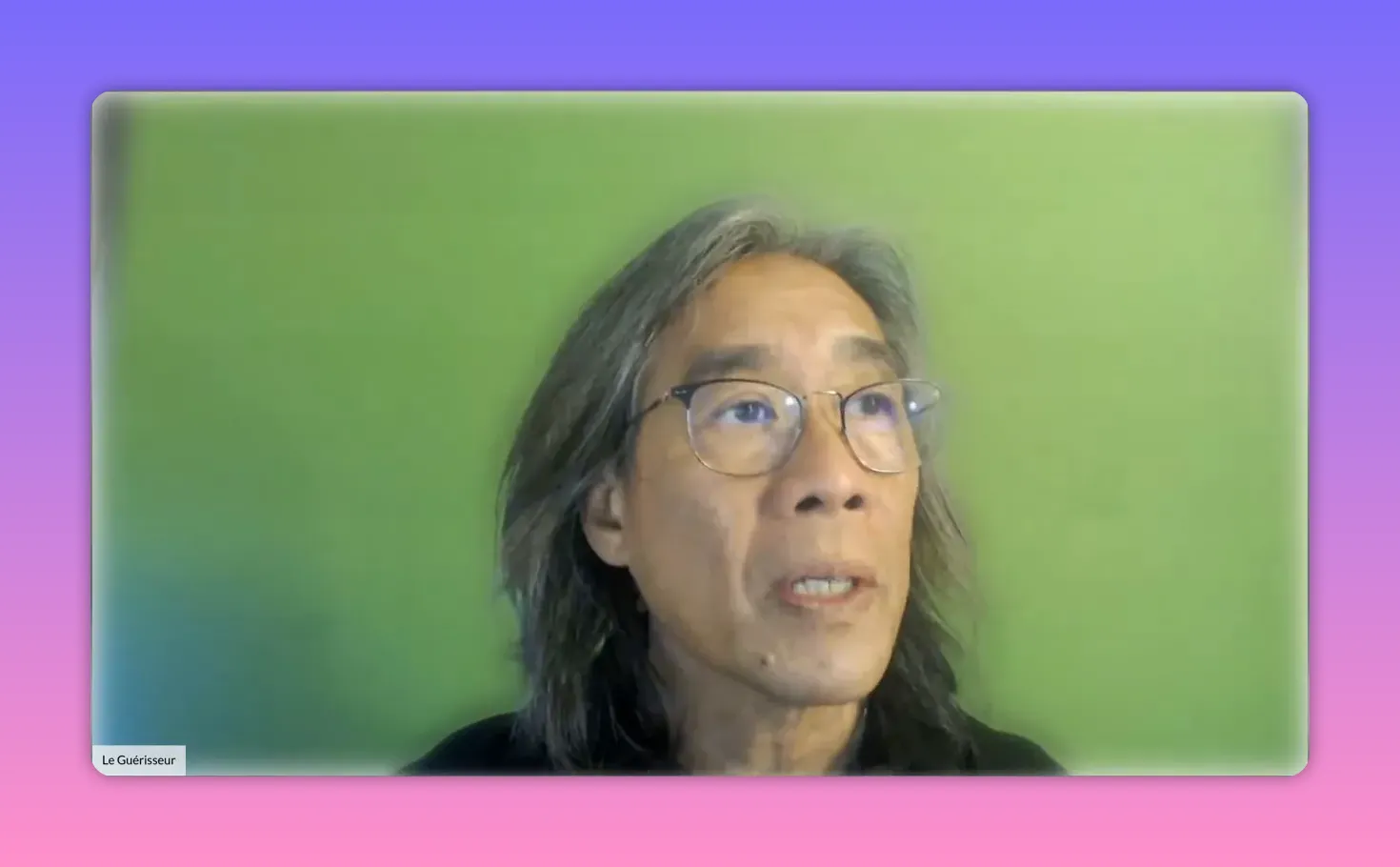 Intervenant regardant légèrement vers le haut sur fond vert, image nette et bien cadrée.