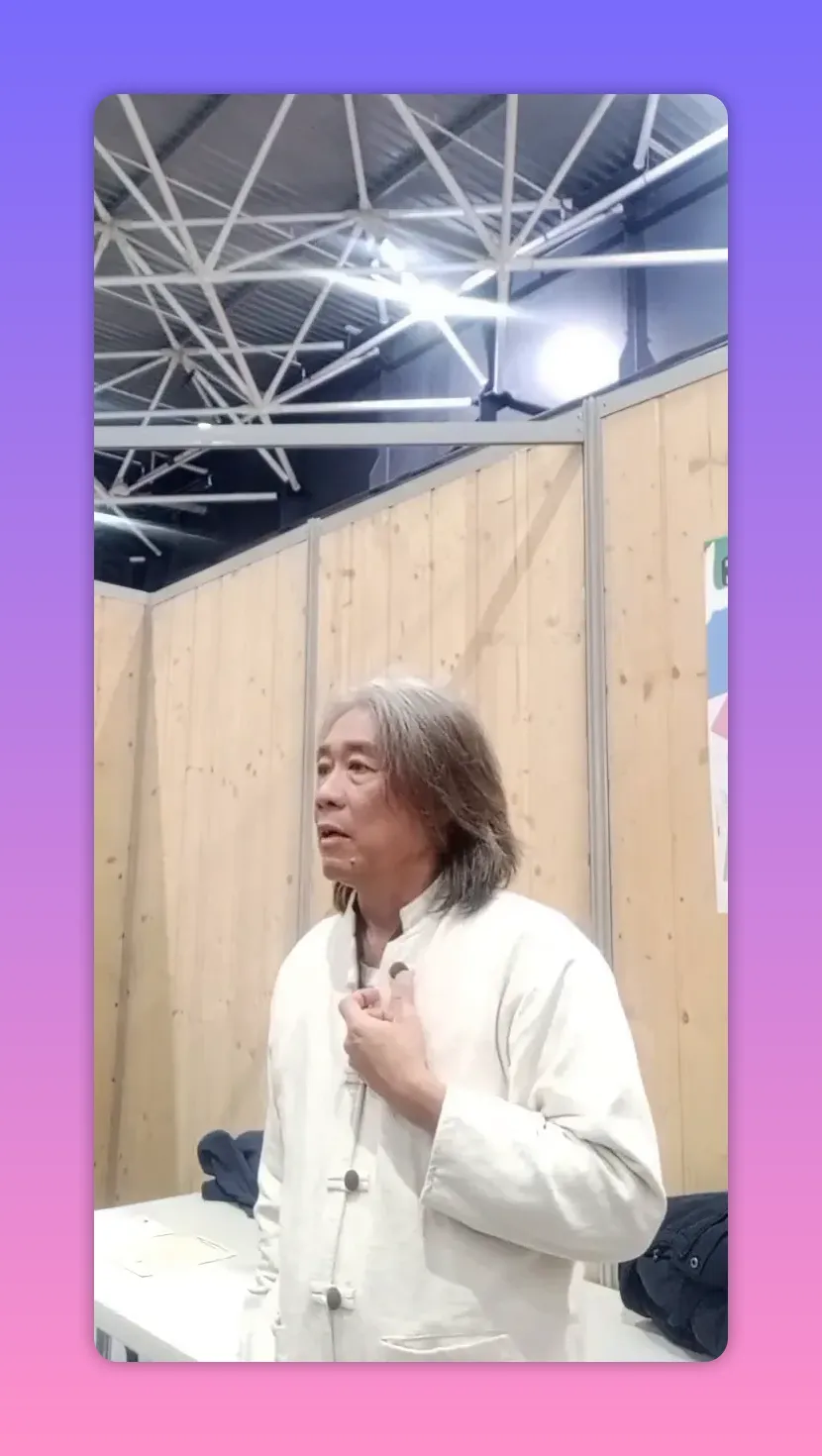 Intervenant en tenue claire, main posée sur la poitrine, regard posé et contemplatif devant des panneaux en bois.