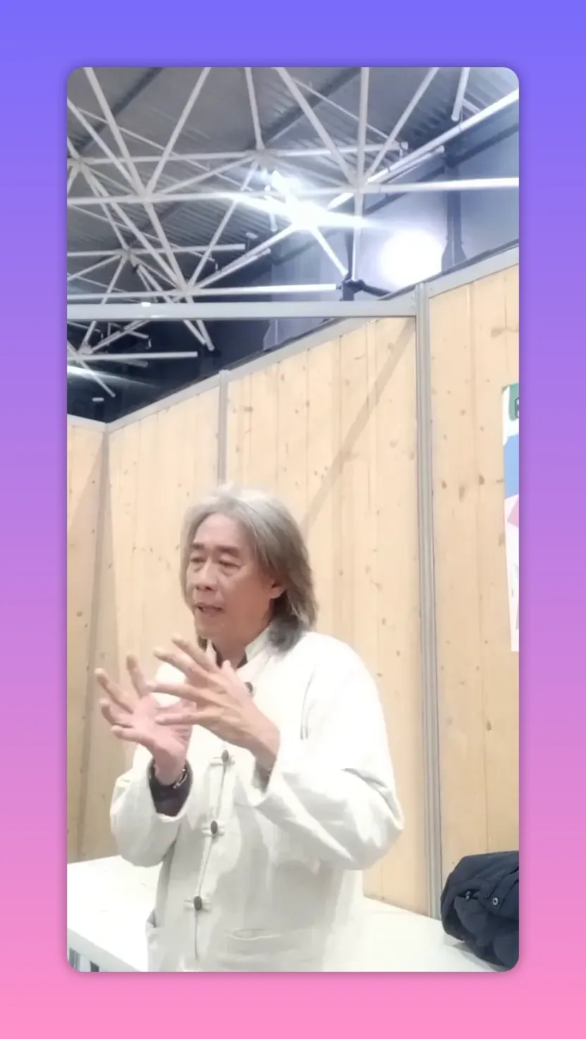 Intervenant montrant un geste des deux mains comme pour tracer ou tenir une idée, regard concentré, veste blanche.