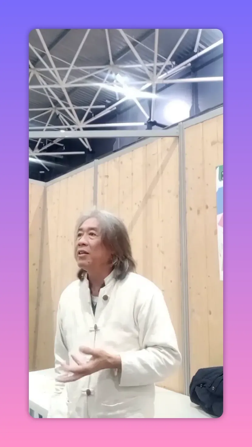 Intervenant regardant légèrement vers le haut, mains en geste d'émission, posture ouverte devant un fond en bois.