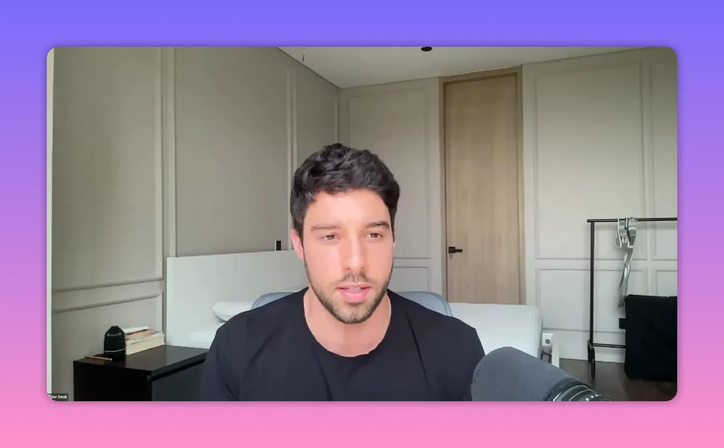 Well-lit video call shot of a guest speaking from a home office with microphone in foreground