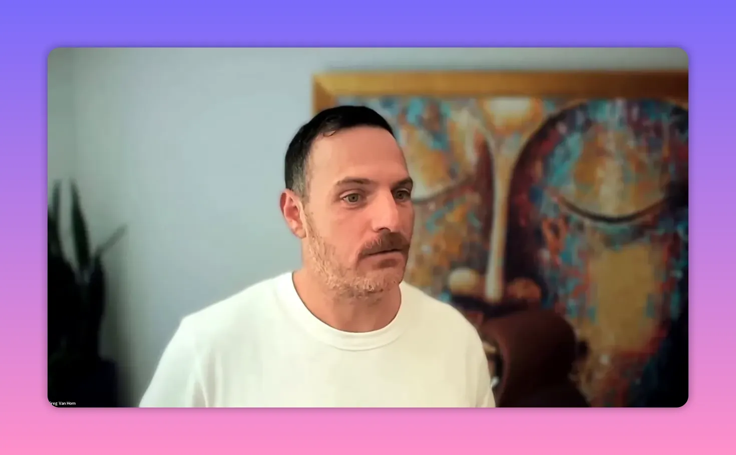 video call screenshot of a speaker in front of decorative artwork, mid-conversation