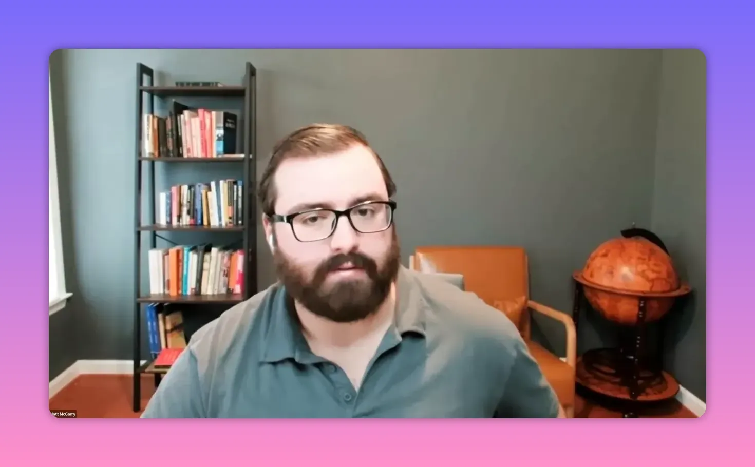 Video speaker centered in a home office with bookshelf and globe, speaking to camera