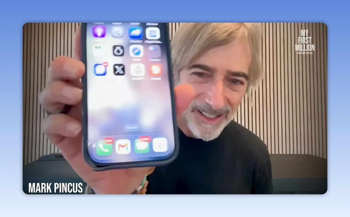 Phone home screen held up to the camera showing app icons across the display
