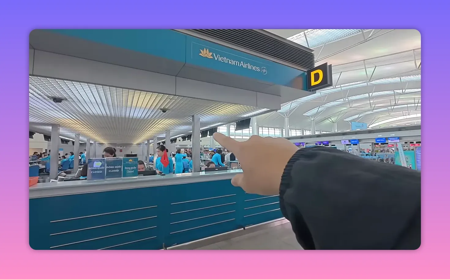 Hand pointing toward the Vietnam Airlines check-in desk and signage in an airport terminal