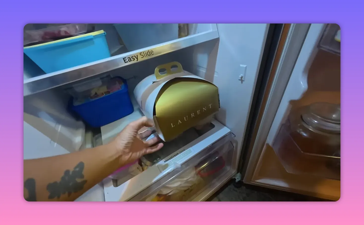 Gold cake box labeled 'LAURENT' inside a refrigerator shelf.