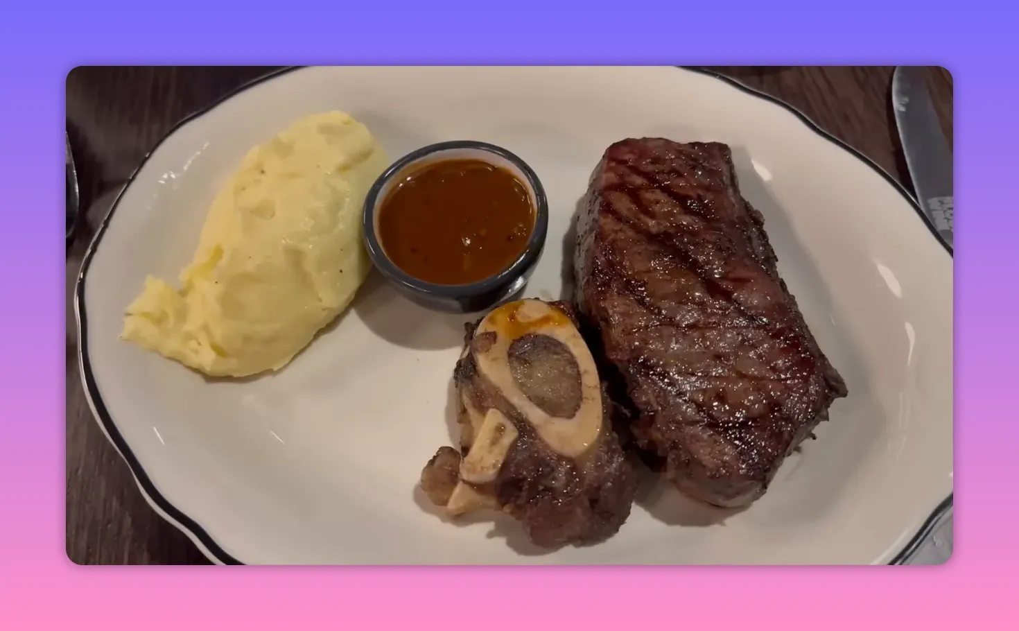 Plate with grilled steak, bone marrow piece, brown sauce in a ramekin and mashed potatoes