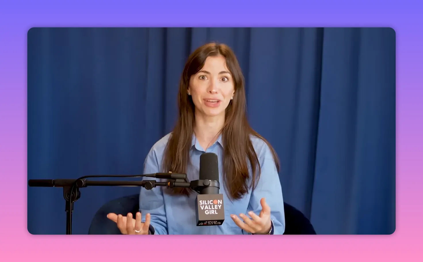 Podcast host speaking emphatically into a microphone with open hands, conveying a persuasive argument, blue curtain background.