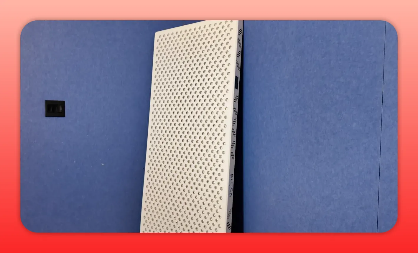 Block Blue Light full-size red light therapy panel leaning against a blue wall, angled view of LEDs