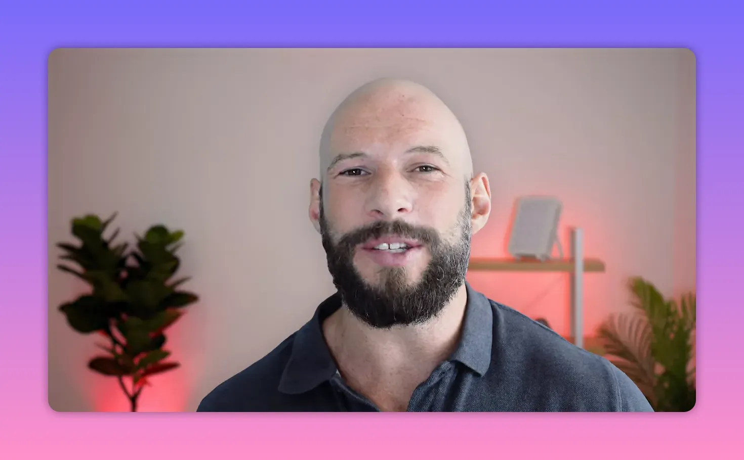 Presenter, centered and facing camera, with a red-lit LED panel on a shelf and plants in the background.